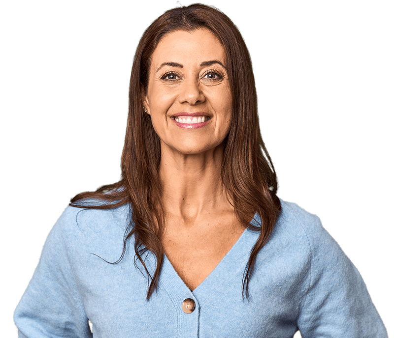 A woman in a blue top stands smiling and looking at the camera.