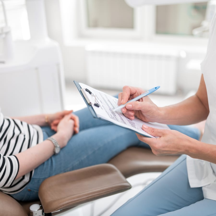 A woman and a receptionist fill out paperwork.
