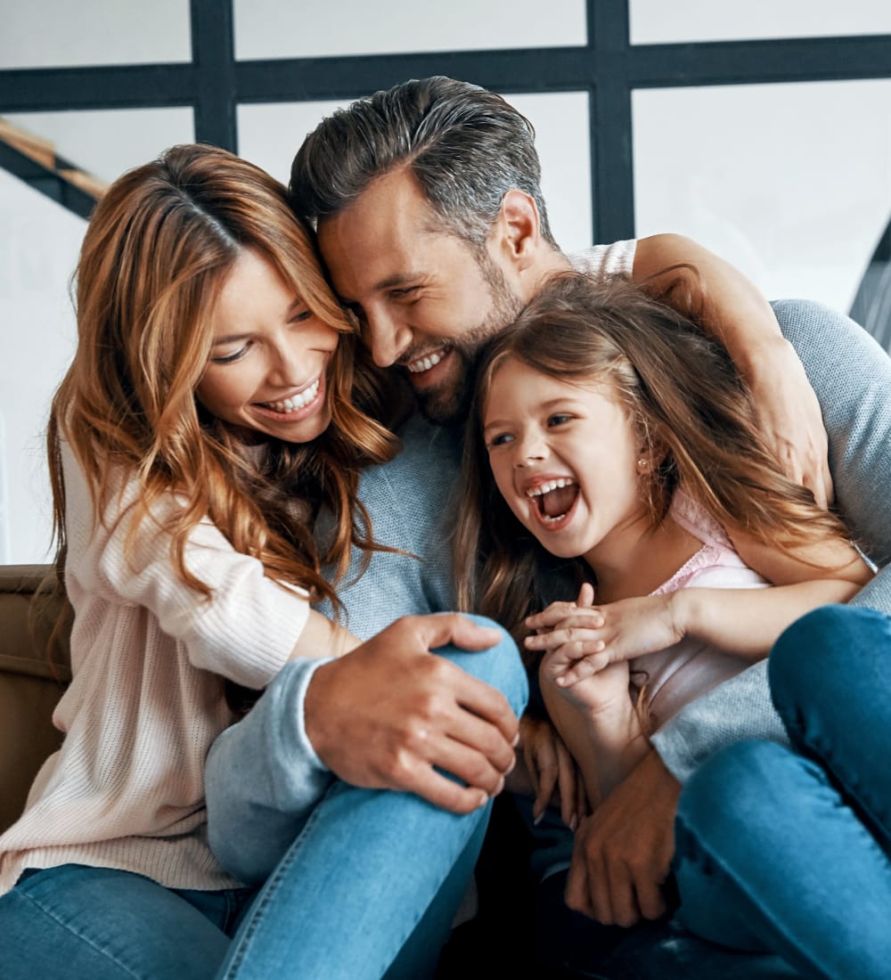 A young family sites together smiling and hugging each other. 